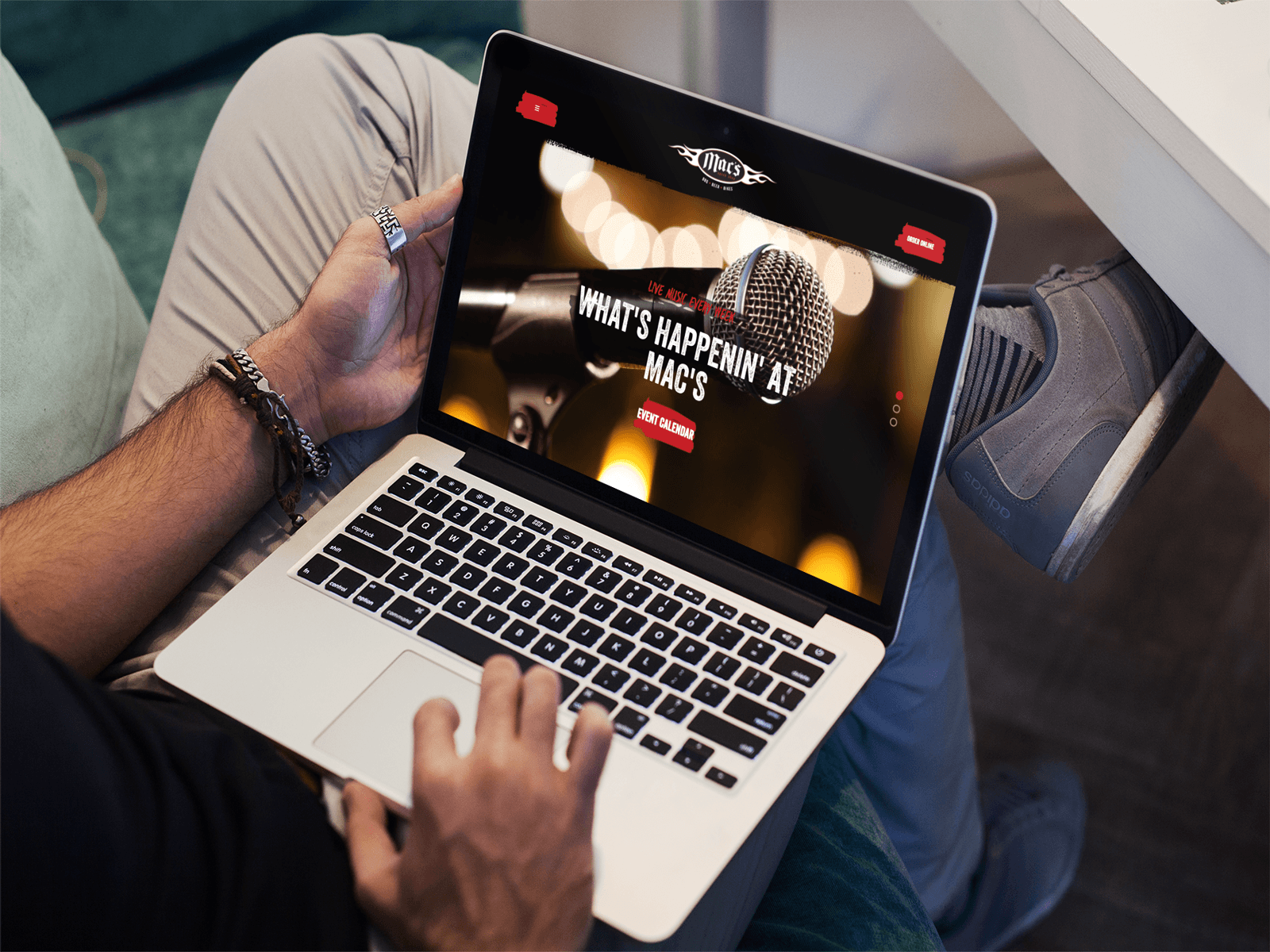 A person is holding a laptop on their lap, browsing a website with a microphone and the text 