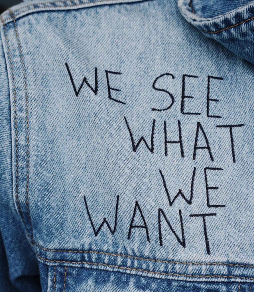 Close-up of a light blue denim jacket with the phrase