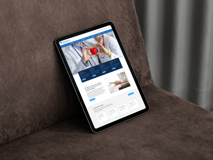 A tablet displaying a medical website rests upright on a brown cushioned surface, showing images of doctors and medical information on its screen.